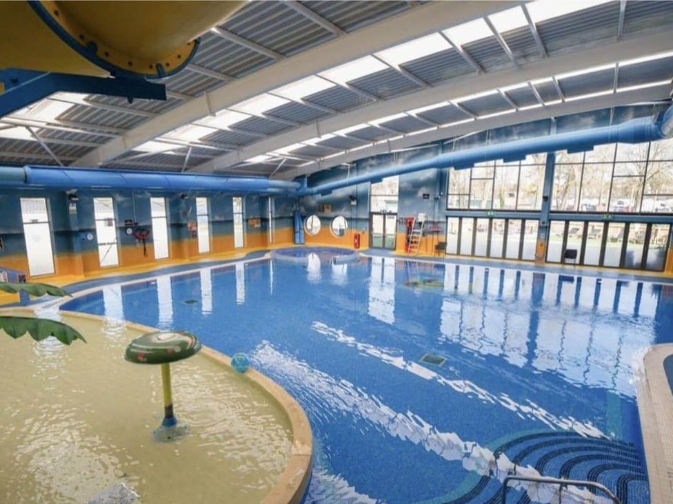An indoor pool with water slide and seating area at Billing Aquadrome Holiday Park 2bed Caravan Northampton