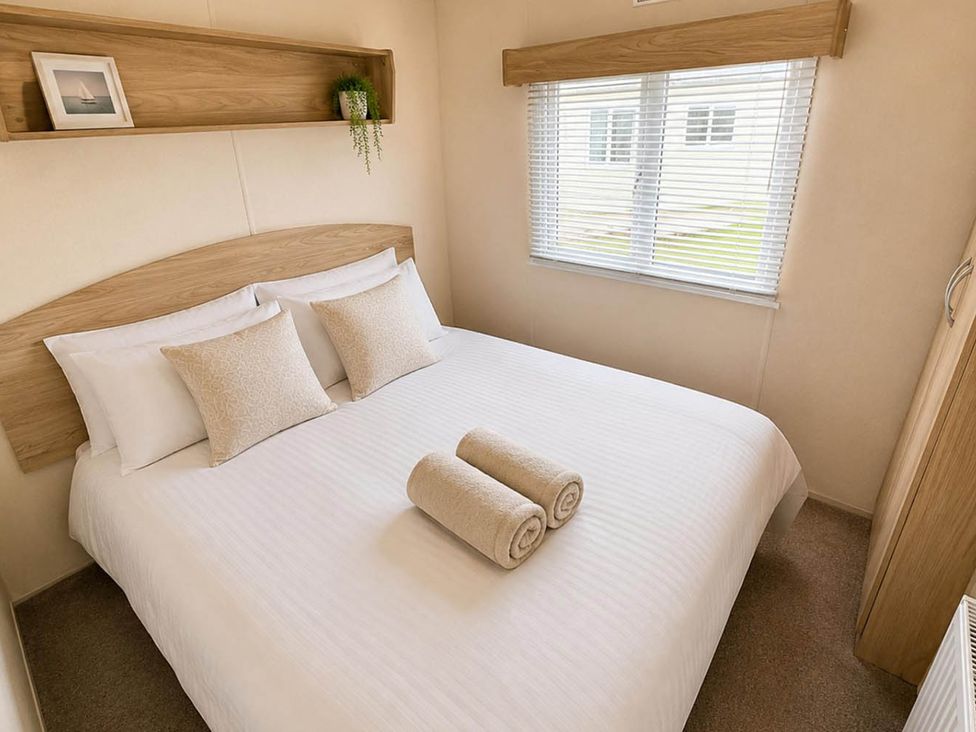 A bedroom with a double bed and towels at Billing Aquadrome Holiday Park 2bed Caravan Northampton