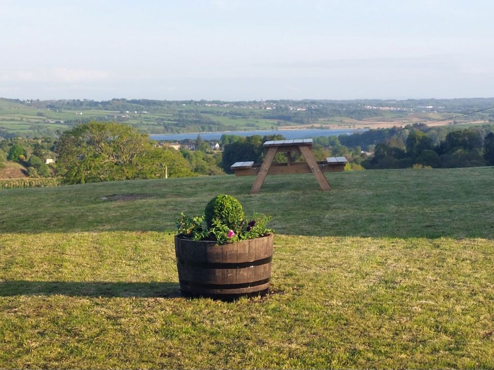An outdoor area with a flower pot and a wooden picnic table near a lake