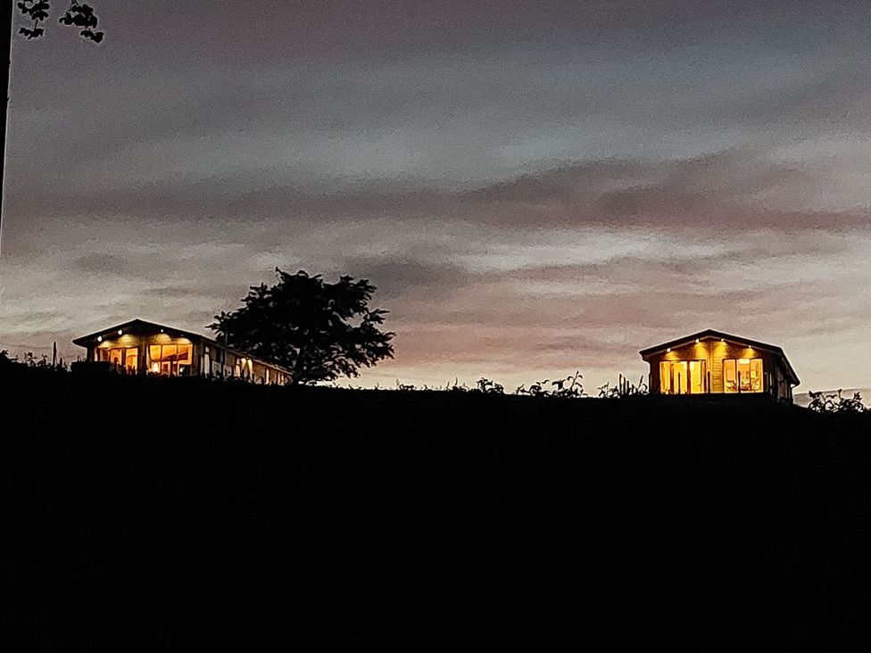 Two houses with lights on at dusk at 2 Bedroom Sleeps 4 Lodge Smart Tv Hot tub Dogs Ok near Lochwinnoch