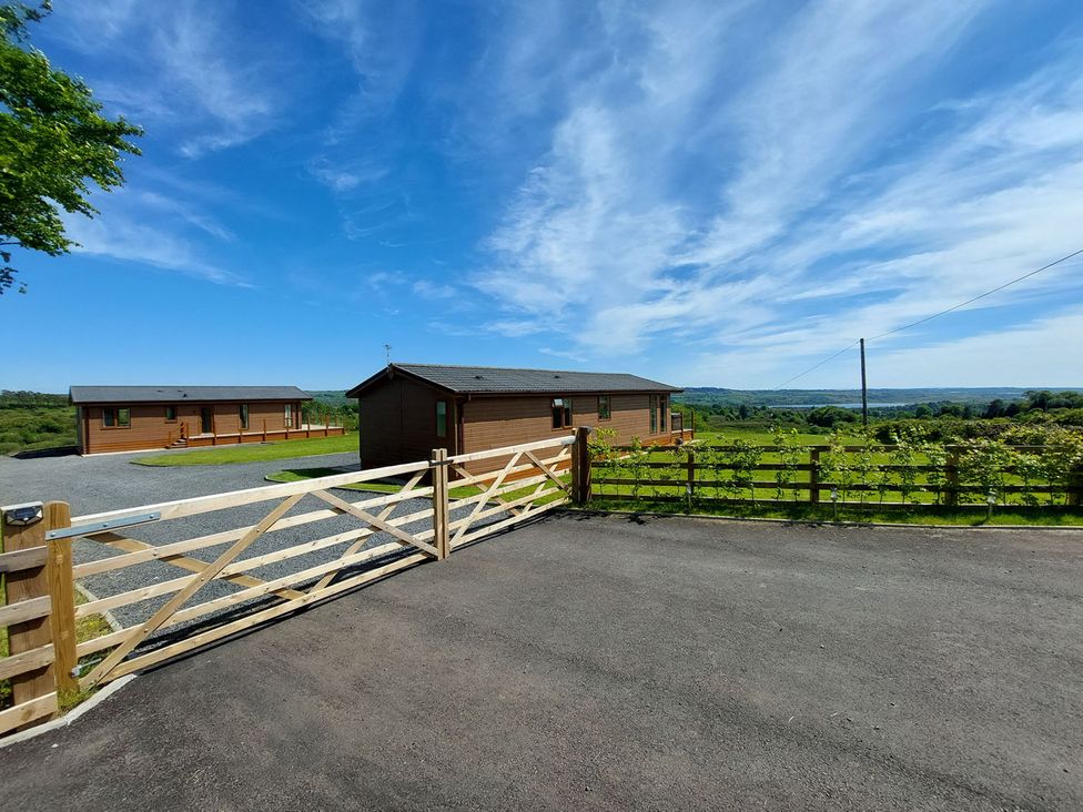 An exterior view of lodges with a gate at 2 Bedroom Sleeps 4 Lodge Smart Tv Hot tub Dogs Ok near Lochwinnoch