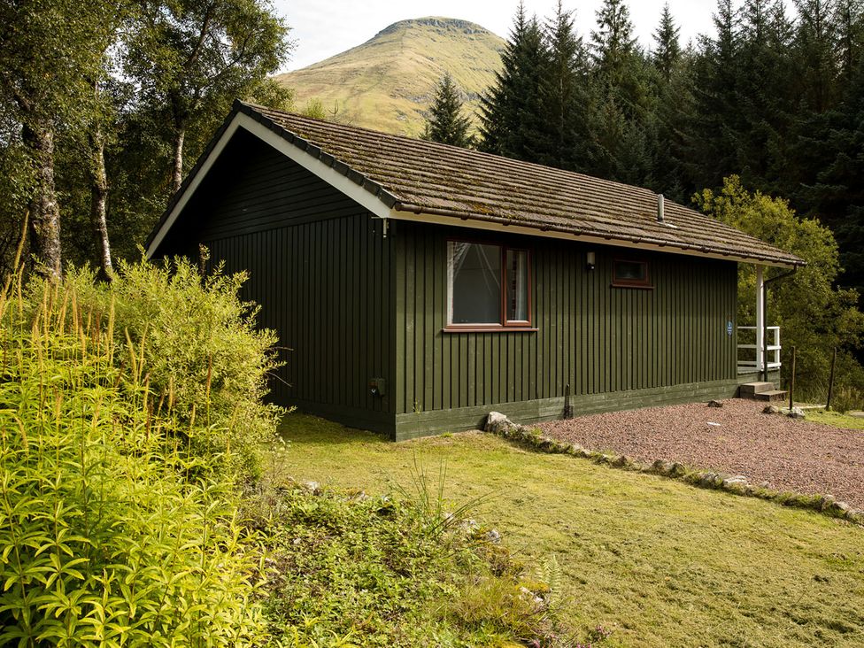 An outdoor view of a lodge surrounded by greenery at 2 bedroom lodge with free WiFi and mountain view near Crianlarich