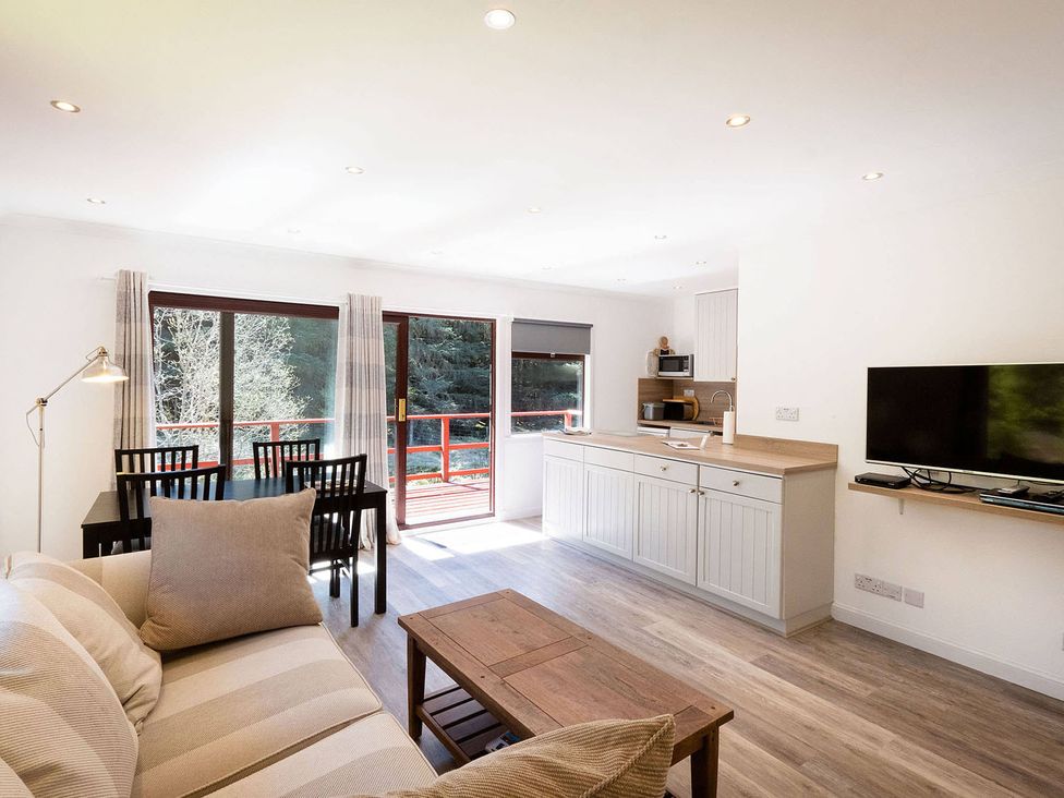A living room with a kitchen area and dining table at 2 bedroom lodge with free WiFi and mountain view near Crianlarich