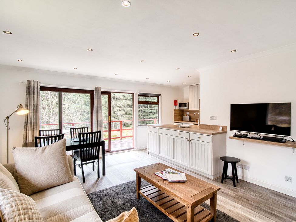 A living room with a dining area and kitchen at 2 bedroom lodge with free WiFi and mountain view near Crianlarich