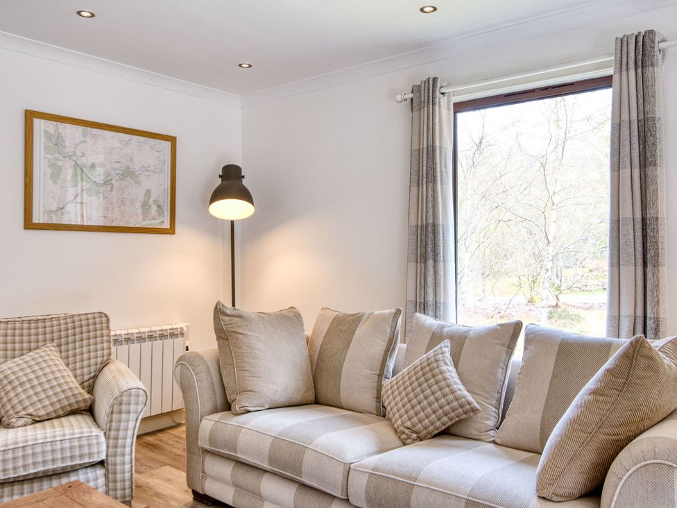 A living room with a couch and lamp at 2 bedroom lodge with free WiFi and mountain view near Crianlarich