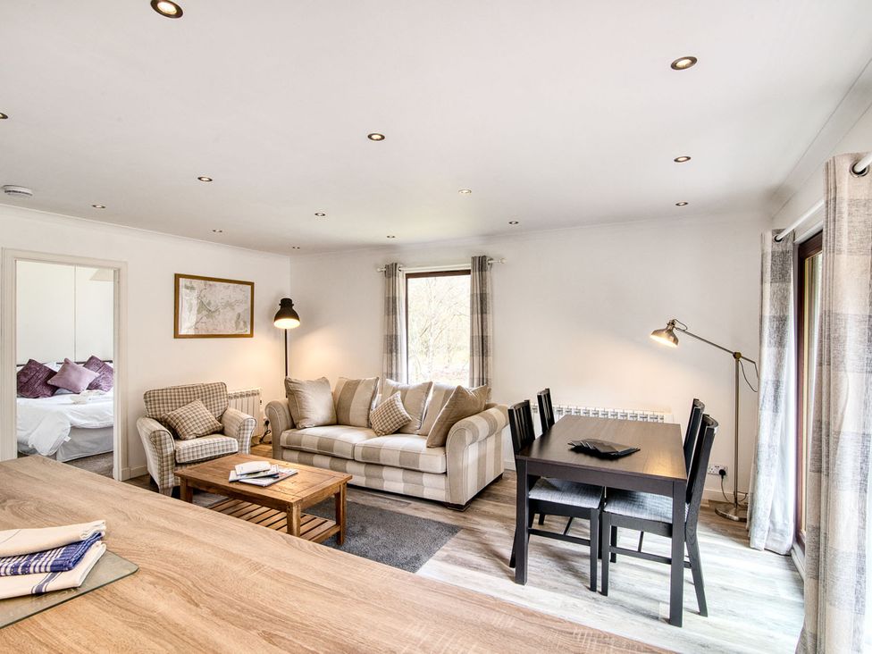 A living room with a sofa and dining area at 2 bedroom lodge with free WiFi and mountain view near Crianlarich