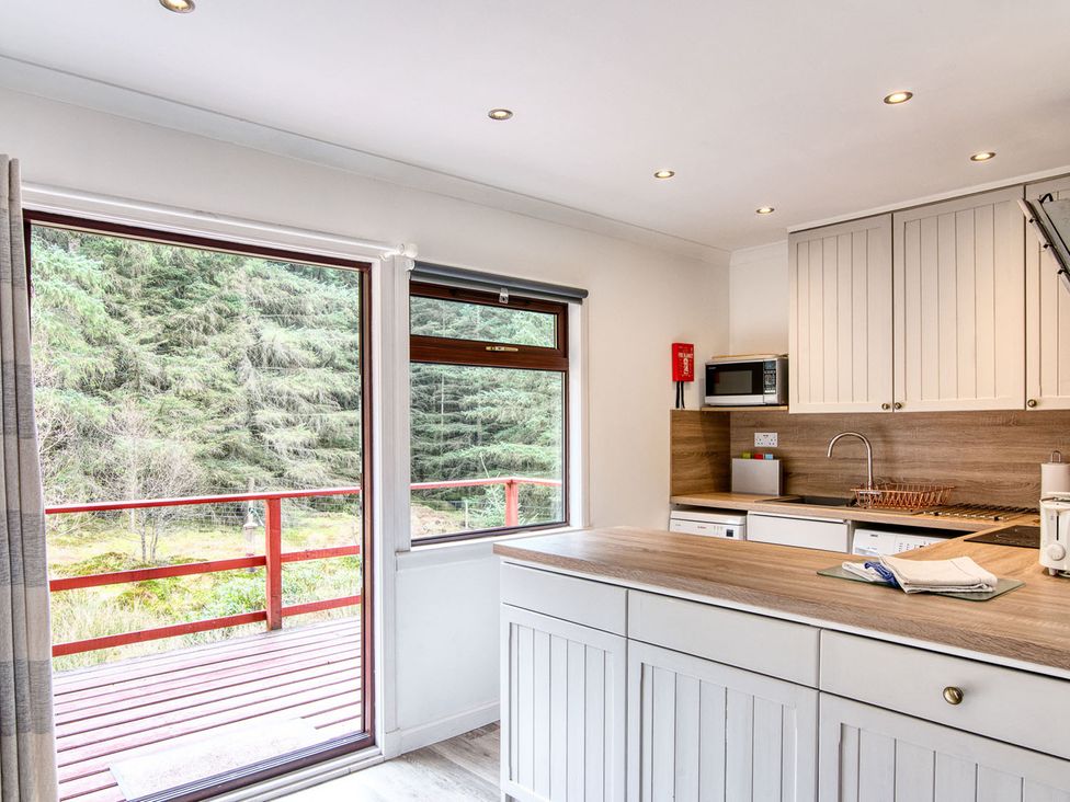 A kitchen with a window and microwave at 2 bedroom lodge with free WiFi and mountain view near Crianlarich