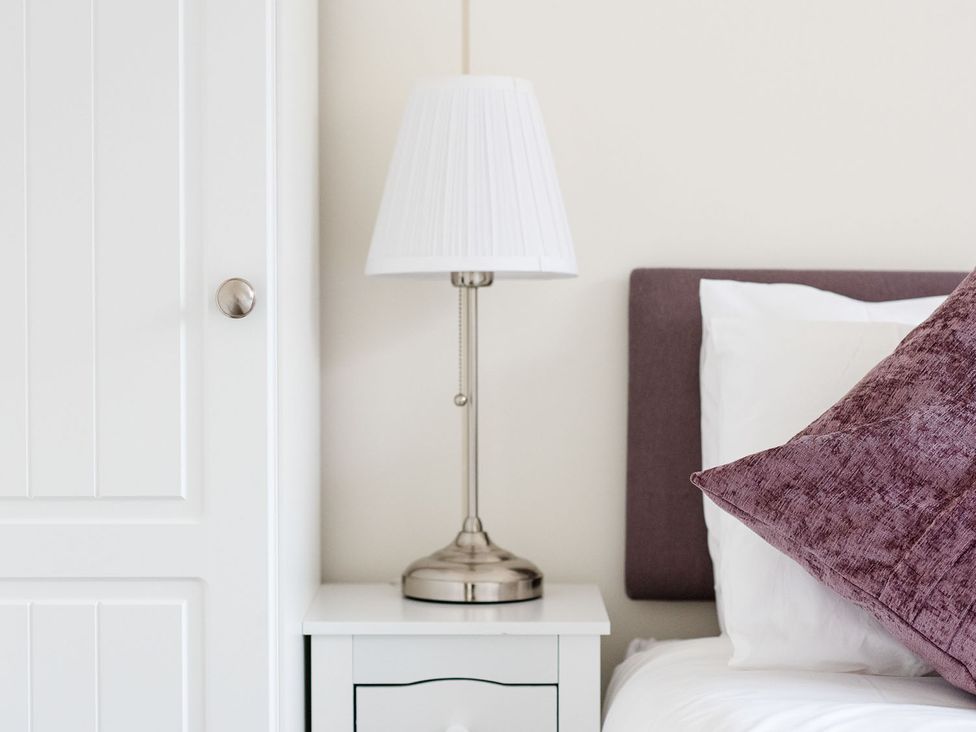 A bedside lamp on a nightstand near a bed at 2 bedroom lodge with free WiFi and mountain view near Crianlarich