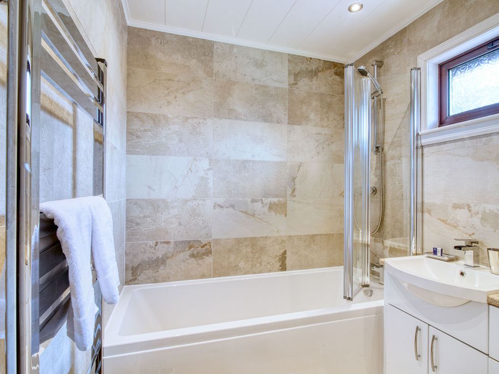 A bathroom with a bathtub and shower in the 2 bedroom lodge with free WiFi and mountain view near Crianlarich