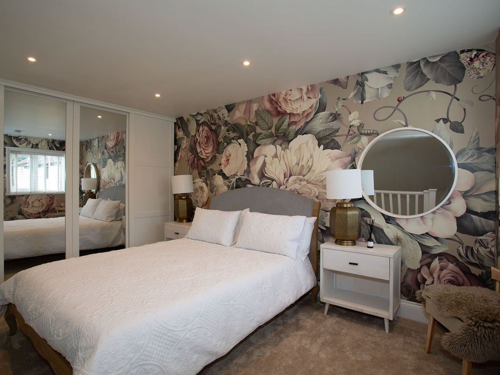 A bedroom with a bed and floral wallpaper at Cozy Wetherby Retreat in Wetherby