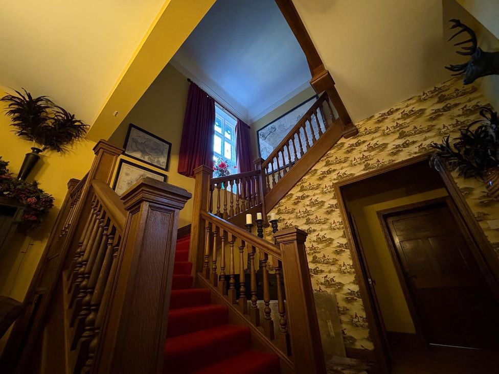 A staircase with wooden handrail and pictures in a stairway at the property