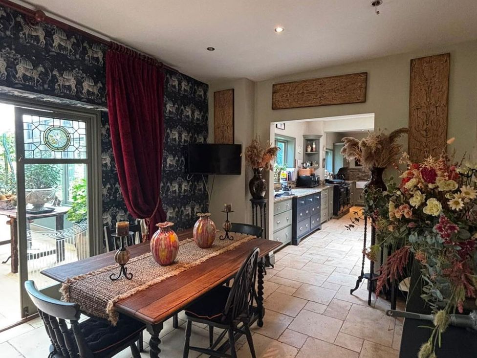 A dining room with a table and chairs leading to a kitchen at the property