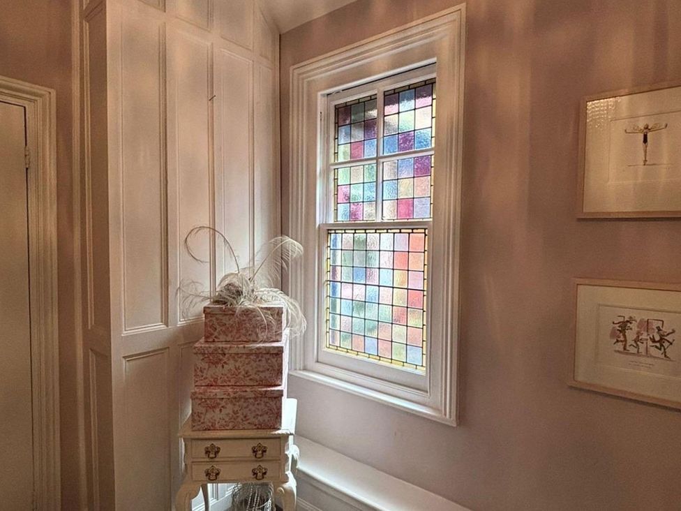 A hallway with a stained glass window and decorative boxes at the property in 