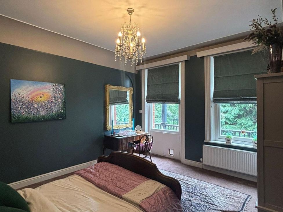 A bedroom with a bed and a desk beside windows at the property in undefined
