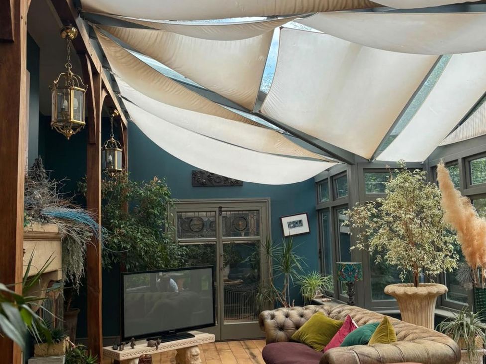 A conservatory with plants and a sofa at The Old Barn in Manchester