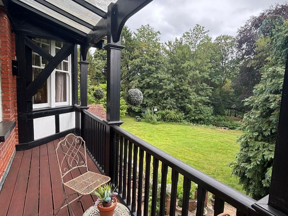 A balcony with a chair and a potted plant overlooking a garden at a property