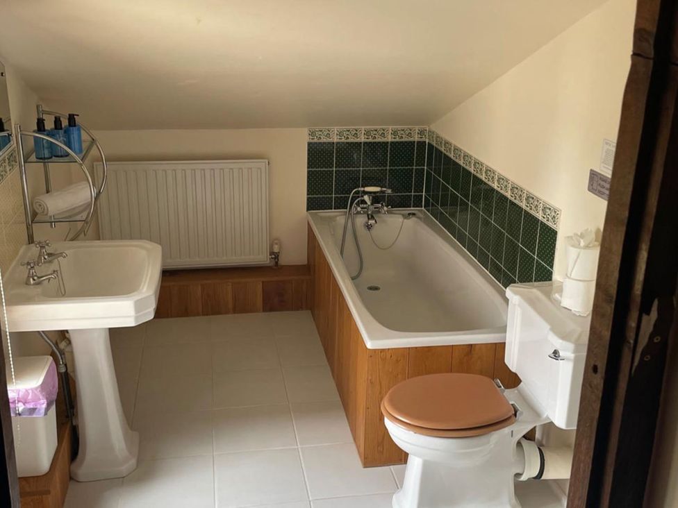 A bathroom with a bathtub, toilet, sink, and radiator at The Old Barn in Manchester