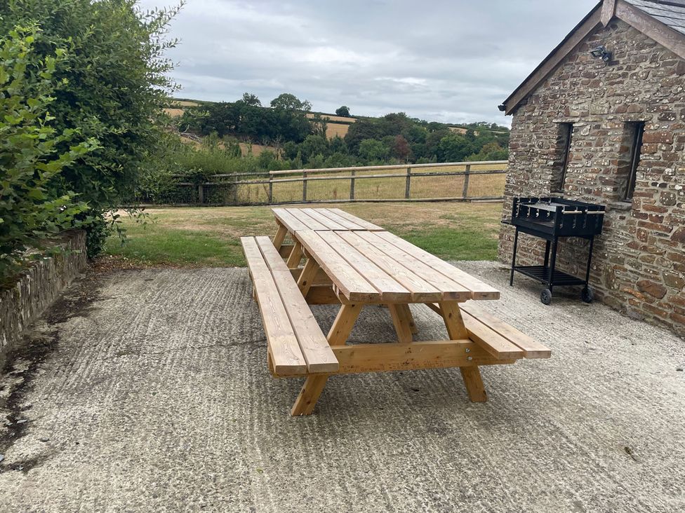An outdoor seating area with a table and benches near a stone building at a property
