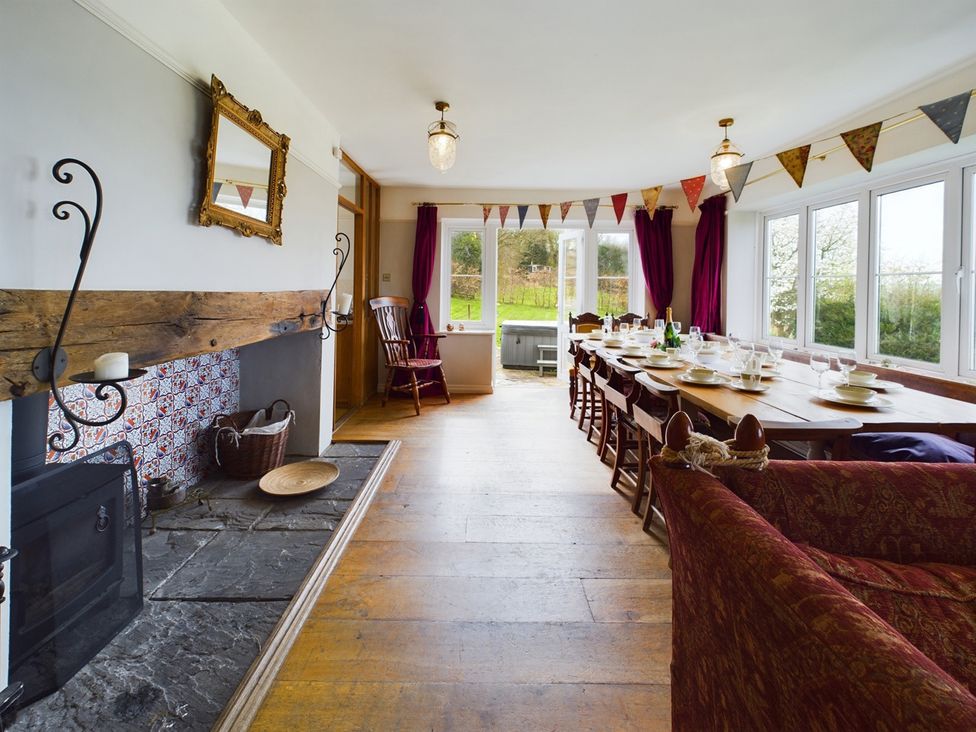 A dining room with a long table and chairs with a fireplace at Country House 14Guests Parking HotTub AmazingViews in Kilgwrrwg near Chepstow