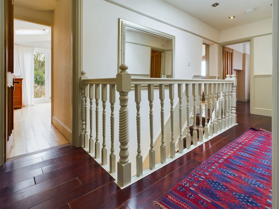 A hallway with a banister and a mirror at Country House 14Guests Parking HotTub AmazingViews Kilgwrrwg near Chepstow