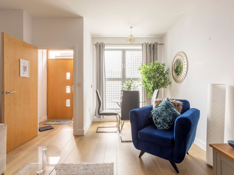 A living room with a blue sofa and a glass table at Queens Lodge Sleeps 2 with Welcome Pack in Redhill