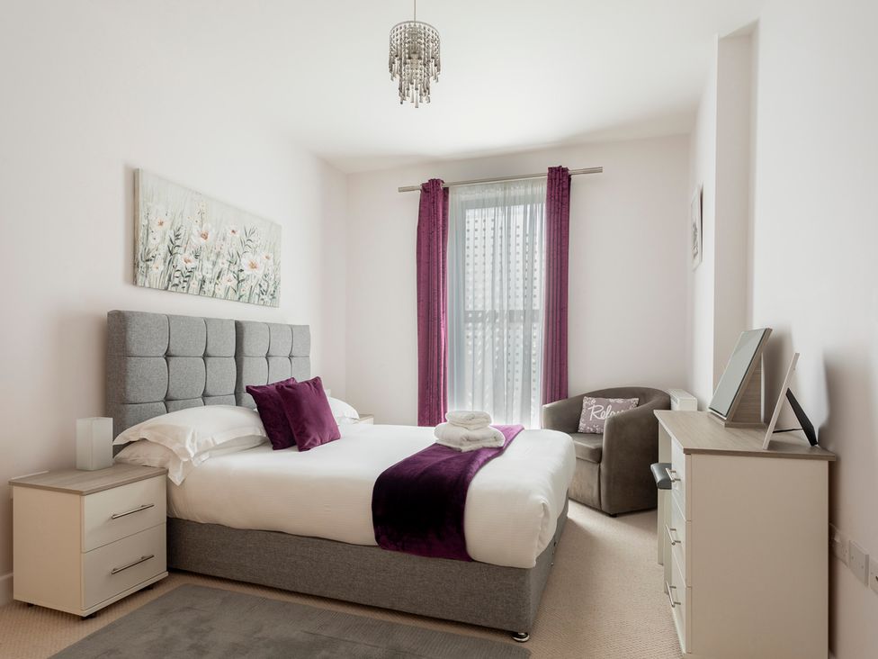 A bedroom with a bed and armchair at Queens Lodge Sleeps 2 with Welcome Pack, Redhill