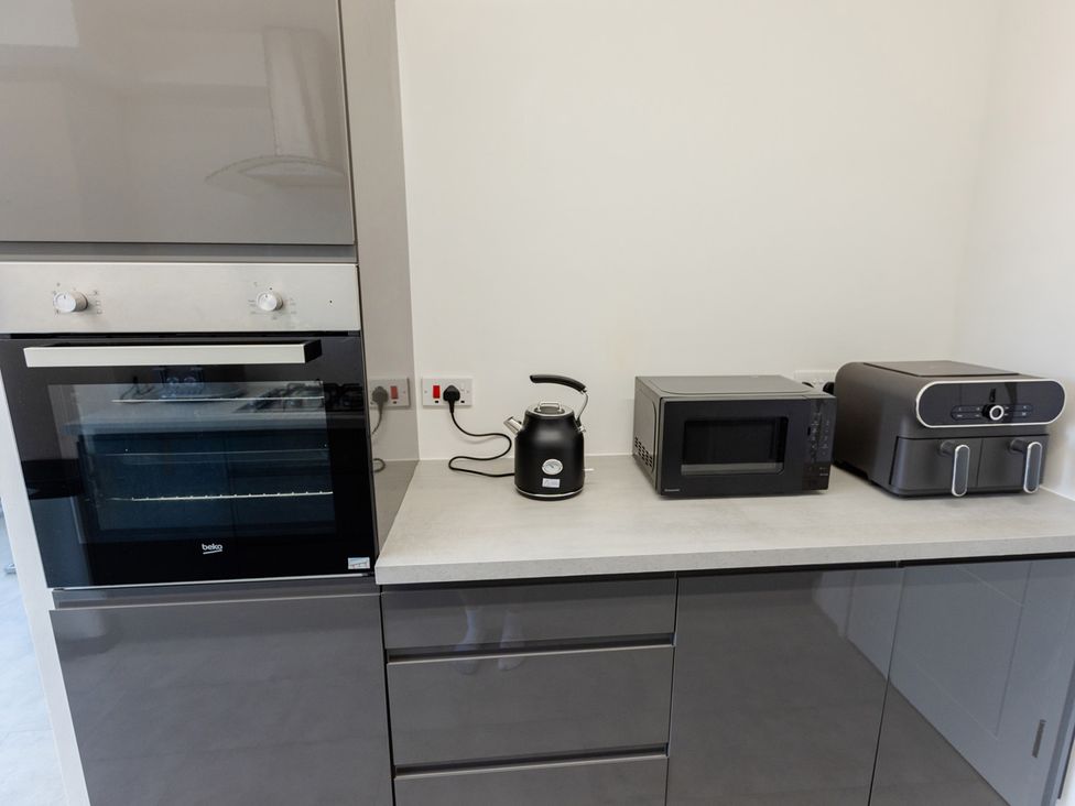 A kitchen with an oven, kettle, microwave, and air fryer at Apartment Sleeps 6 Parking WiFi in Guildford