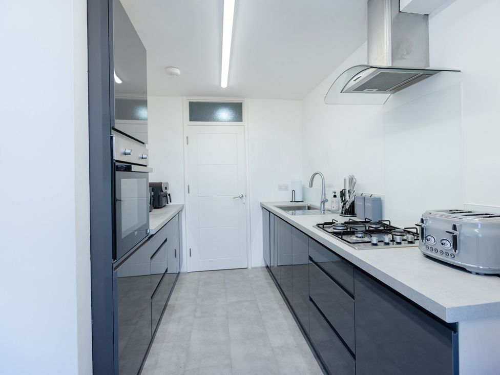 A kitchen featuring an oven, microwave, sink, and gas stove at Apartment Sleeps 6 Parking WiFi in Guildford