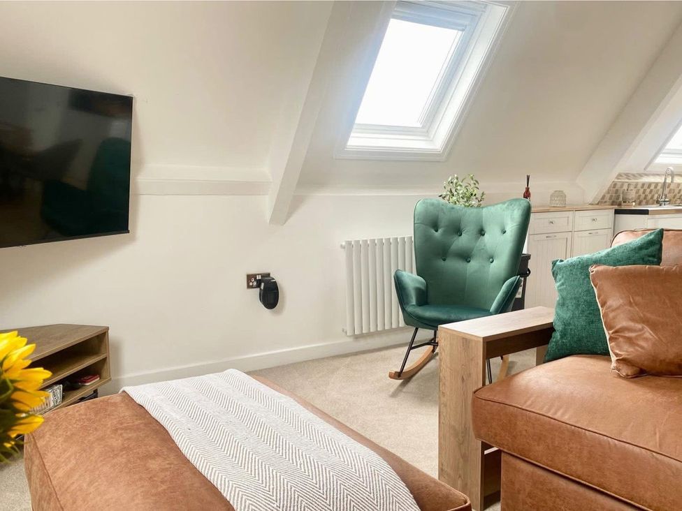 A living room with a television and a rocking chair at Central Tenby 3 Bed Apt Sleeps 6 to 8 Dog Friendly, Tenby