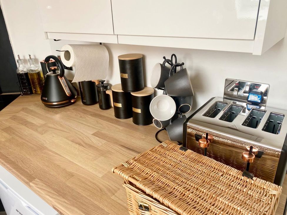 A kitchen counter with kettle, toaster, cups and a basket at Central Tenby 3 Bed Apt Sleeps 6 to 8 Dog Friendly in Tenby