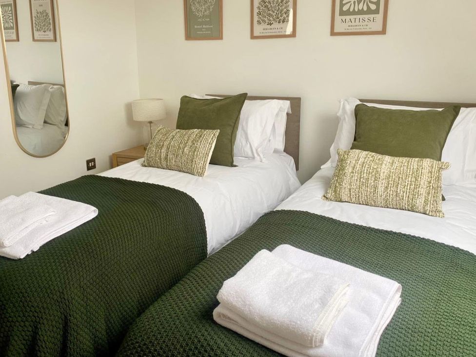 A bedroom with two beds and decorative items at Central Tenby 3 Bed Apt Sleeps 6 to 8 Dog Friendly in Tenby