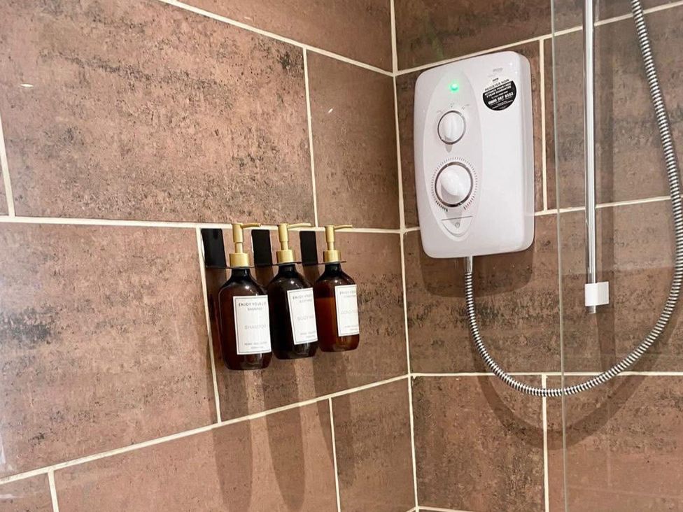 A shower with shampoo bottles and a shower unit at Central Tenby 3 Bed Apt Sleeps 6 to 8 Dog Friendly in Tenby