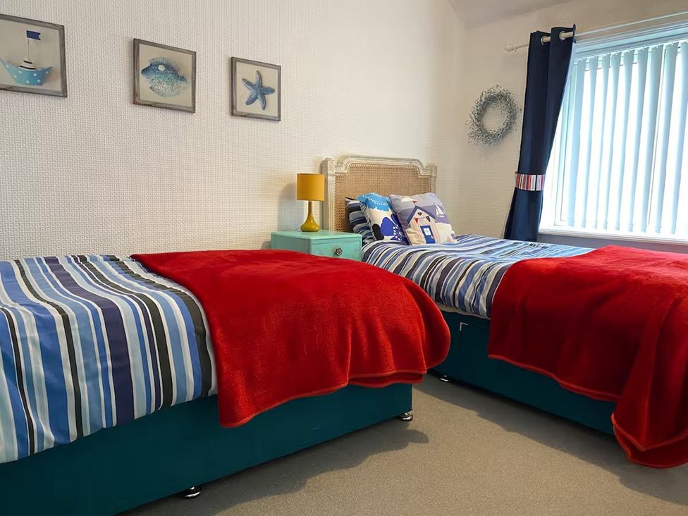 A bedroom with two beds and a lamp at 5 Bed Villa Sleeps 10 Pets Garden Parking Skegness