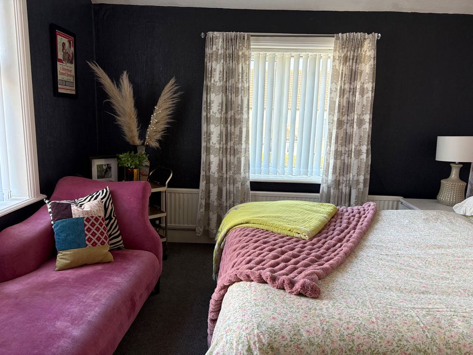A bedroom with a bed and a sofa at 5 Bed Villa Sleeps 10 Pets Garden Parking Skegness