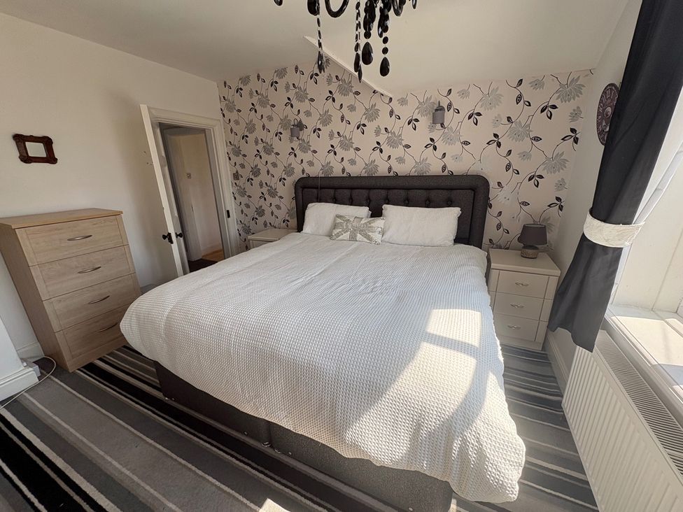 A bedroom with a bed and nightstand at 5 Bed Villa Sleeps 10 Pets Garden Parking Skegness