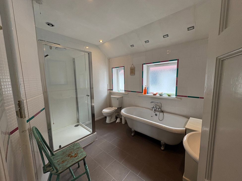 A bathroom with a shower, bathtub, toilet, and chair at 5 Bed Villa Sleeps 10 Pets Garden Parking Skegness