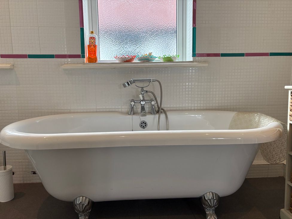 A bathtub with faucet and shelf in a bathroom at 5 Bed Villa Sleeps 10 Pets Garden Parking in Skegness
