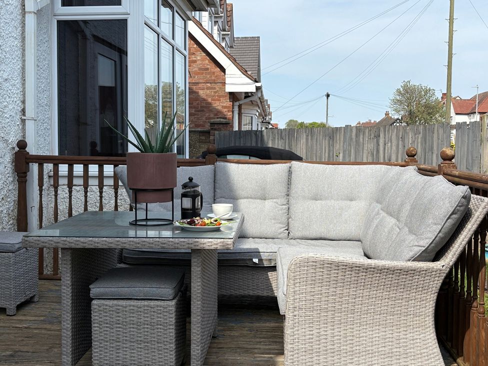 An outdoor seating area with a table and couch at 5 Bed Villa Sleeps 10 Pets Garden Parking in Skegness