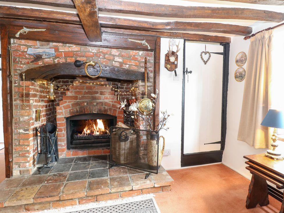 A living room with a fireplace and wooden beams at Hollyhedge Cottage in Briston