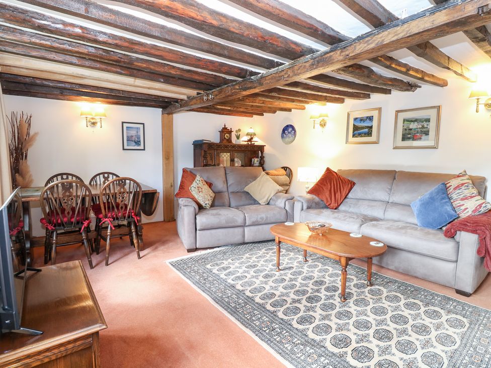 A living room with a sofa, coffee table, and dining table at Hollyhedge Cottage in Briston