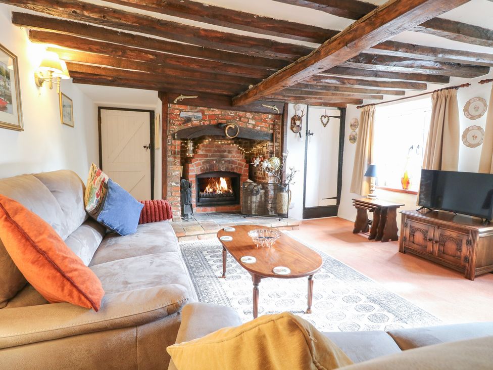 A living room with a fireplace, sofa, and coffee table at Hollyhedge Cottage in Briston