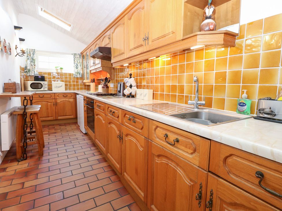 A kitchen with wooden cabinets and a sink at Hollyhedge Cottage in Briston