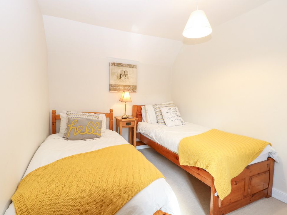 A bedroom with two single beds and a lamp at Hollyhedge Cottage in Briston