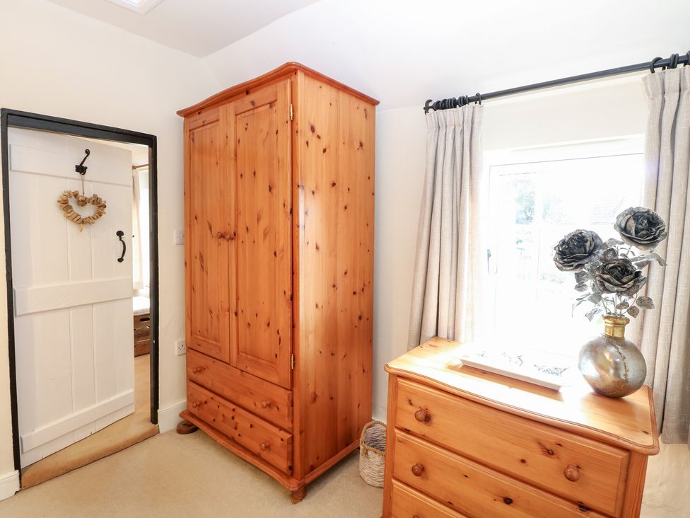 A bedroom with wardrobe and dressing table at Hollyhedge Cottage Briston