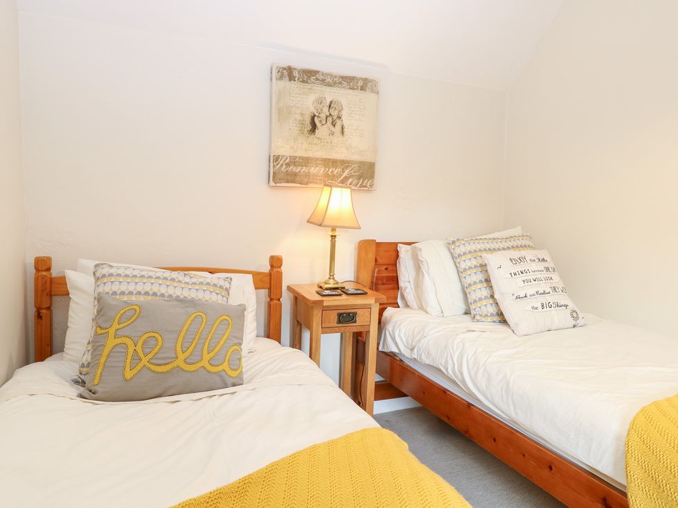 A bedroom with two beds and a lamp at Hollyhedge Cottage in Briston