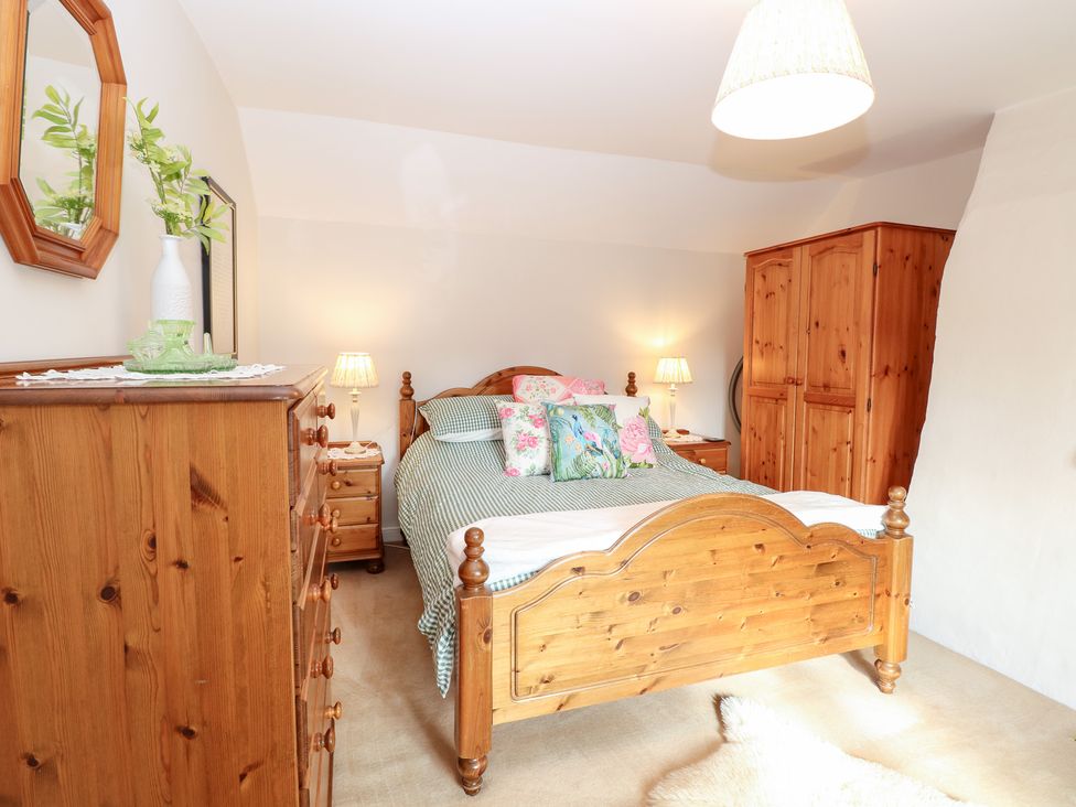 A bedroom with wooden furniture and a bed at Hollyhedge Cottage in Briston