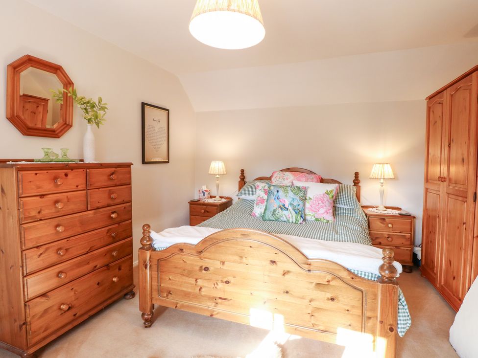 A bedroom with a bed and wooden furniture at Hollyhedge Cottage in Briston