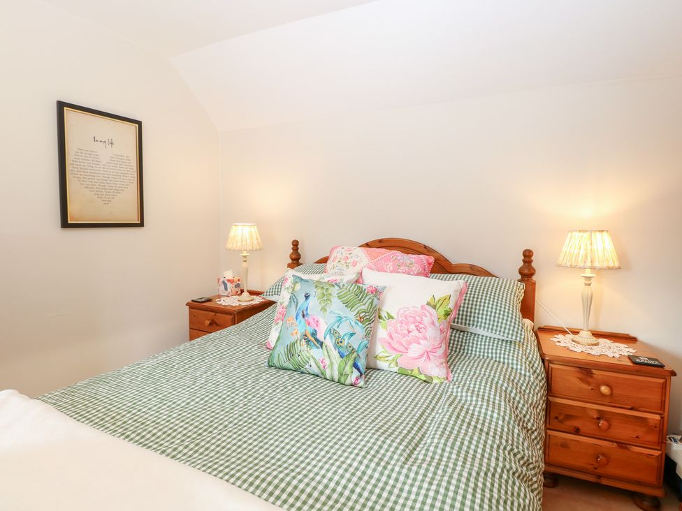 A bedroom with a bed, pillows, and a lamp at Hollyhedge Cottage, Briston