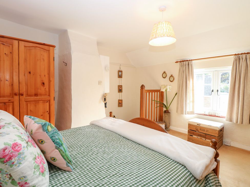 A bedroom with a bed and wardrobe at Hollyhedge Cottage Briston