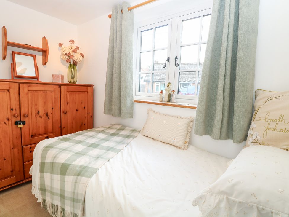 A bedroom with a bed and a cabinet at Hollyhedge Cottage in Briston